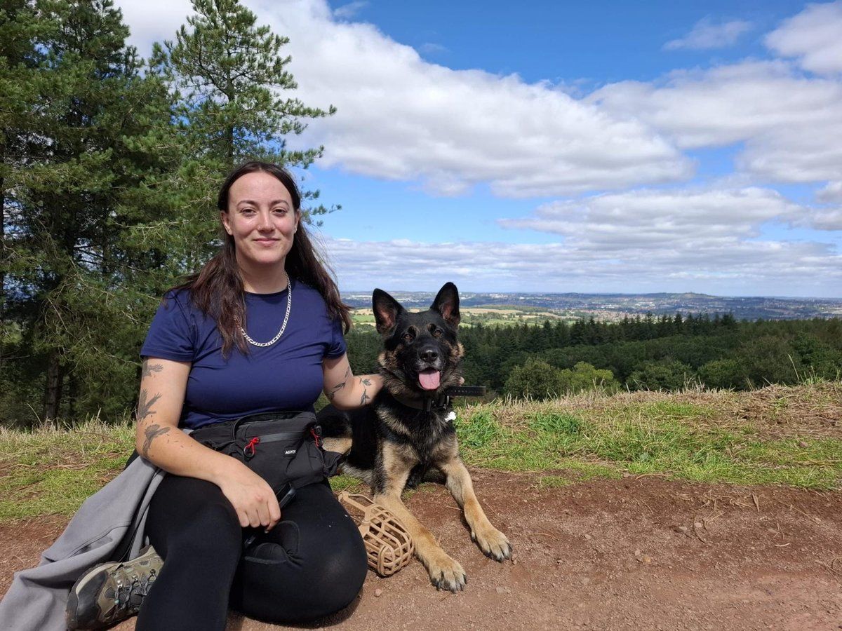Tamar sitting on a hilltop with her German Shepherd